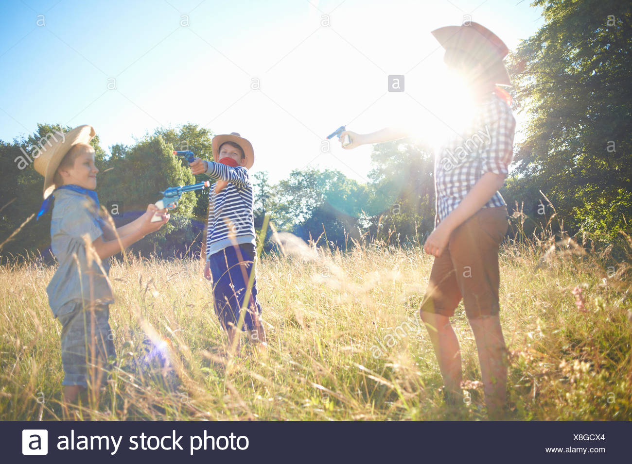 Tre giovani ragazzi vestito da cowboy, tenendo pistole giocattolo Foto Stock