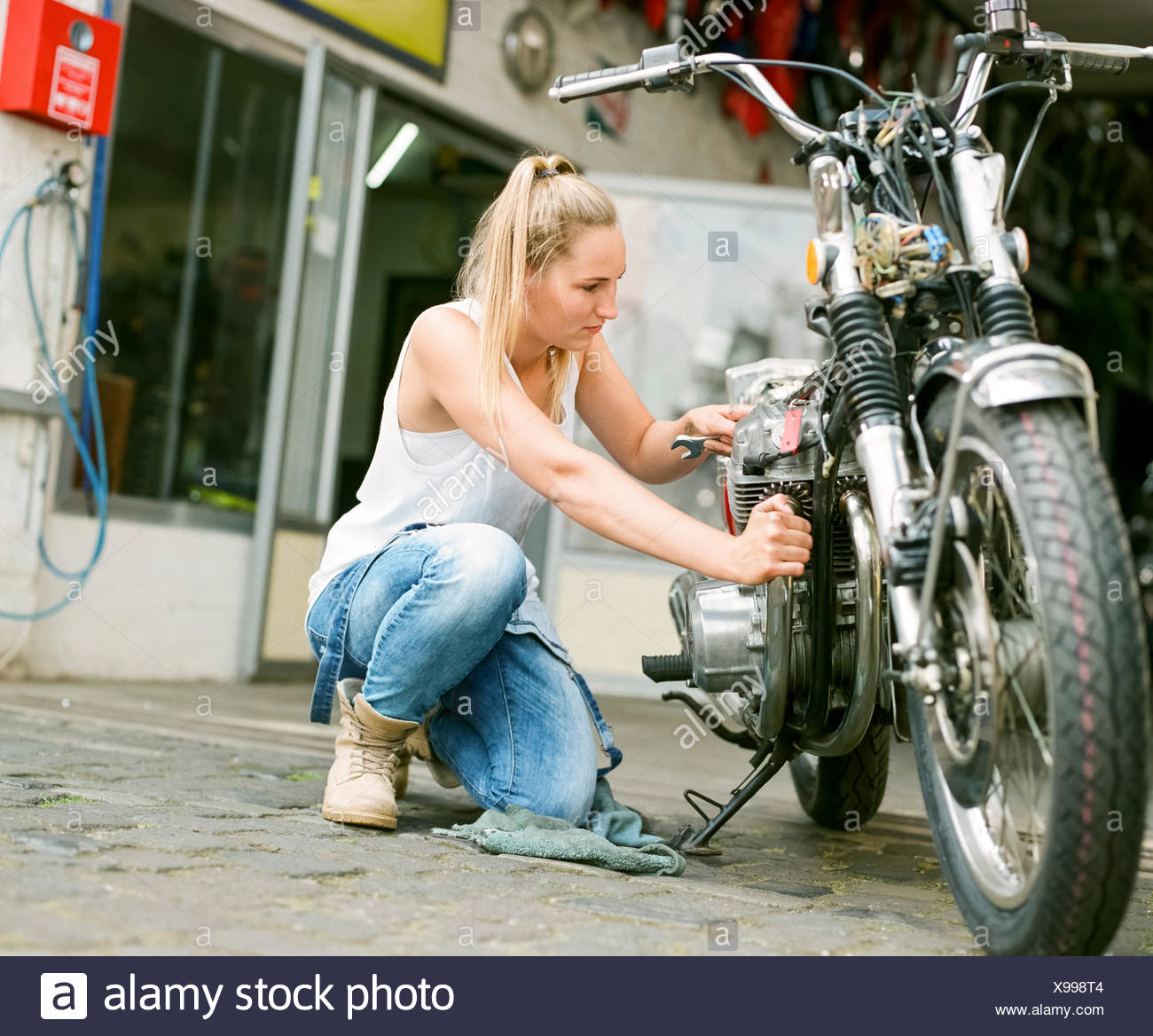 Giovane donna riparazione di moto Foto stock - Alamy