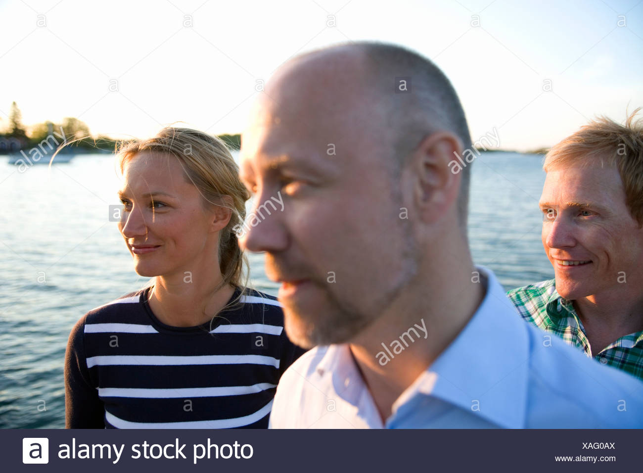 Tre persone in piedi dall'acqua, Fejan, arcipelago di Stoccolma, Svezia. Foto Stock