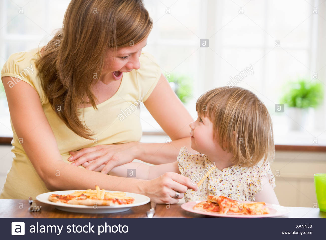 Donna Incinta Con La Figlia Di Toccare La Pancia Di Mangiare Patatine Fritte E Pizza Foto Stock Alamy