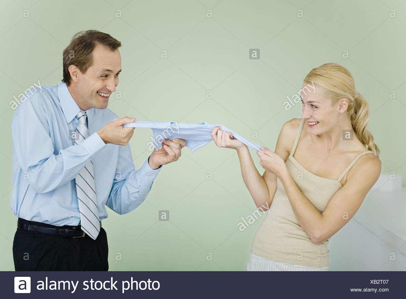 Matura in lotta per i vestiti del bambino, sorridente ad ogni altro Foto Stock