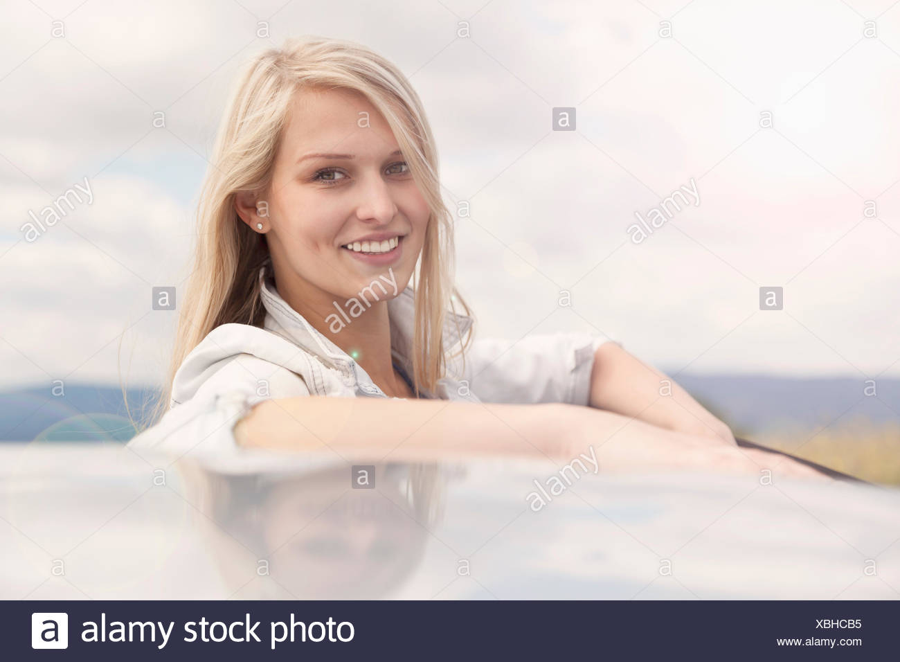Giovane donna sorridente accanto a AUTO Foto Stock