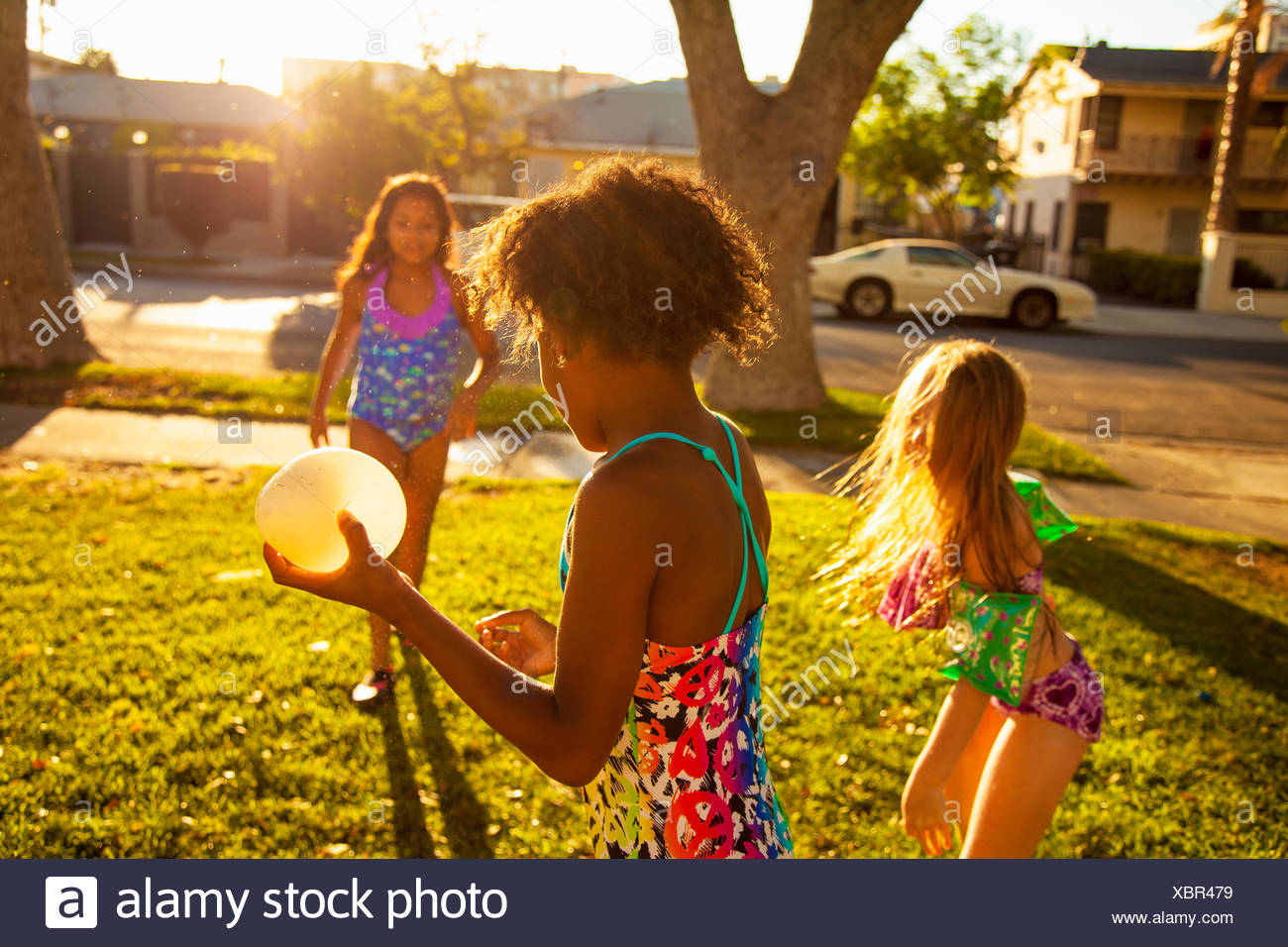 Le tre ragazze giocare con acqua palloncini in giardino Foto Stock