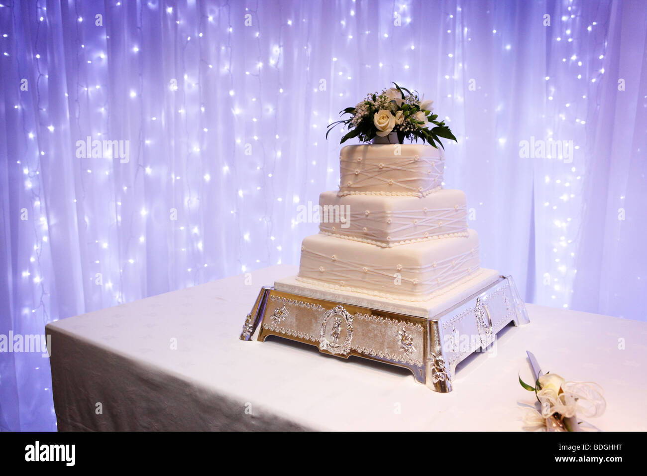 Three Tiered White Wedding Cake On Ornate Silver Stand With Cake